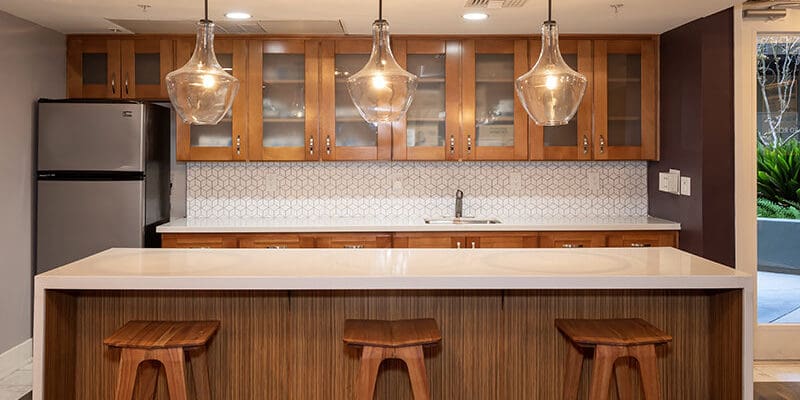 kitchen island with stools and a refrigerator in the background